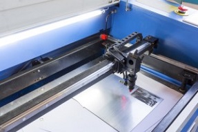 Laser machine is cutting an image on a flat sheet ot steel in a university laboratory.